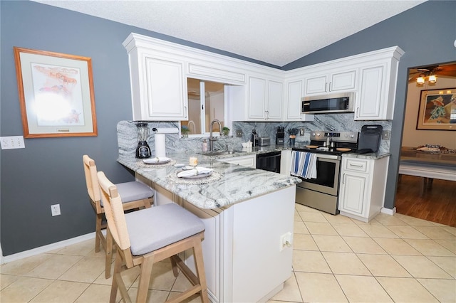 kitchen featuring light tile patterned flooring, a breakfast bar, sink, white cabinets, and stainless steel appliances