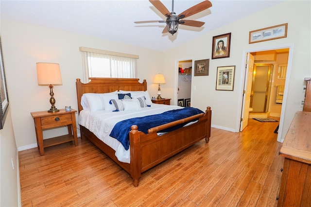 bedroom with vaulted ceiling, a spacious closet, ceiling fan, light wood-type flooring, and a closet