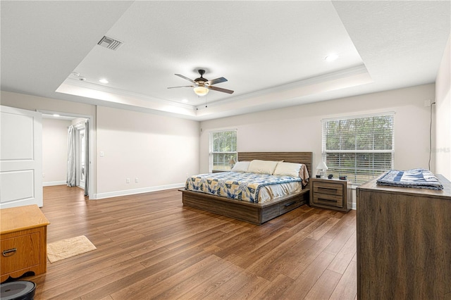 bedroom featuring hardwood / wood-style flooring, ceiling fan, and a tray ceiling