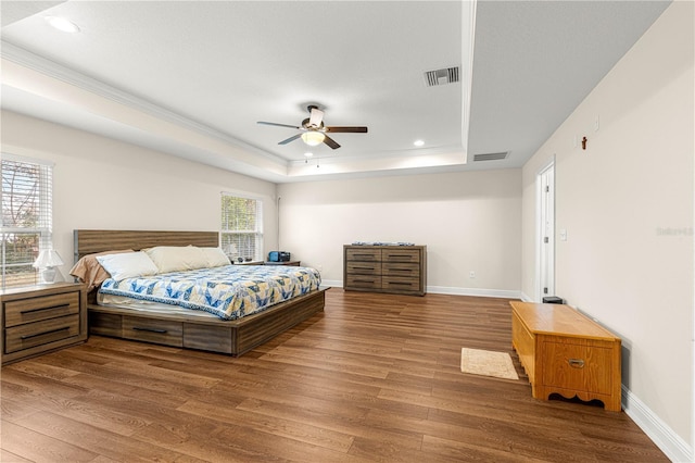 bedroom featuring hardwood / wood-style flooring, ornamental molding, a raised ceiling, and ceiling fan