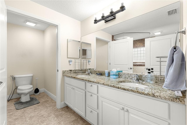 bathroom featuring vanity, toilet, and a textured ceiling