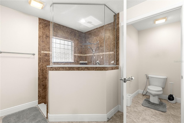 bathroom featuring a tile shower and toilet