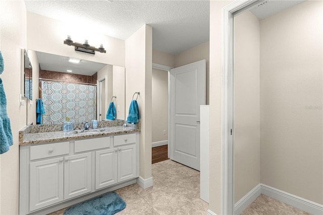 bathroom with a shower with curtain, vanity, tile patterned flooring, and a textured ceiling