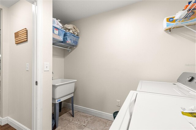 laundry area with washer and dryer and light tile patterned floors