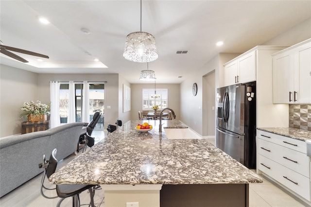 kitchen with a spacious island, white cabinetry, stainless steel fridge with ice dispenser, and backsplash