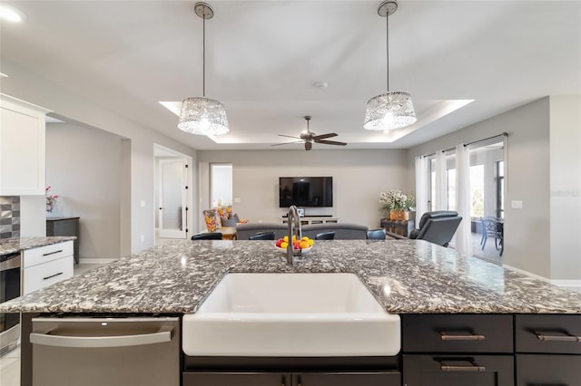 kitchen with white cabinetry, a raised ceiling, sink, and light stone counters