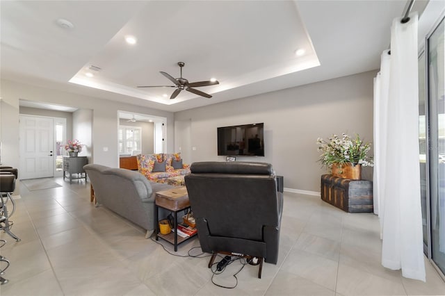 living room featuring a tray ceiling and ceiling fan