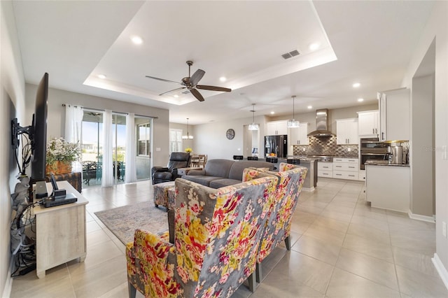 tiled living room featuring a raised ceiling and ceiling fan