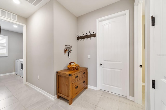 hallway featuring light tile patterned floors and washer / dryer