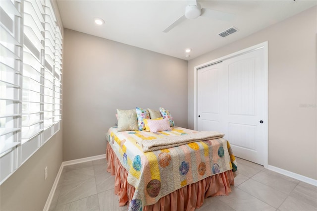 tiled bedroom with ceiling fan and a closet