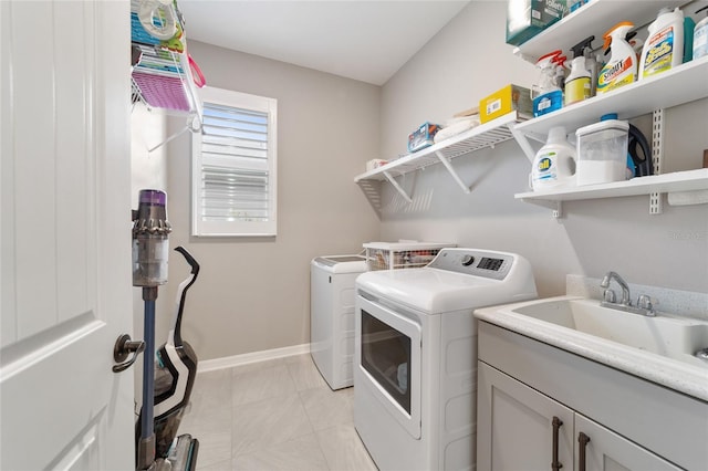 clothes washing area with cabinets, sink, and independent washer and dryer