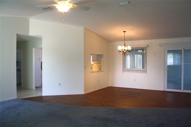 carpeted empty room featuring ceiling fan with notable chandelier, vaulted ceiling, and a textured ceiling