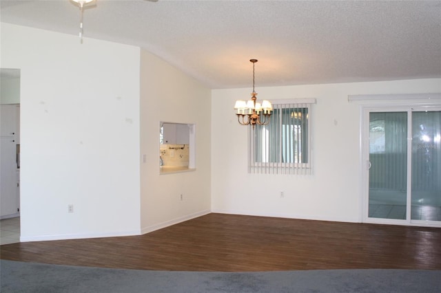 empty room featuring dark hardwood / wood-style flooring, a notable chandelier, vaulted ceiling, and a textured ceiling