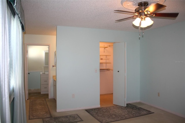 bedroom with ceiling fan, a walk in closet, a closet, and a textured ceiling