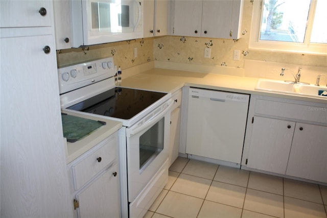 kitchen featuring sink, white appliances, light tile patterned floors, and white cabinets