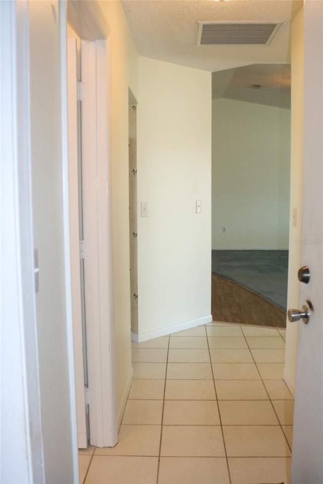 hallway featuring a textured ceiling and light tile patterned flooring