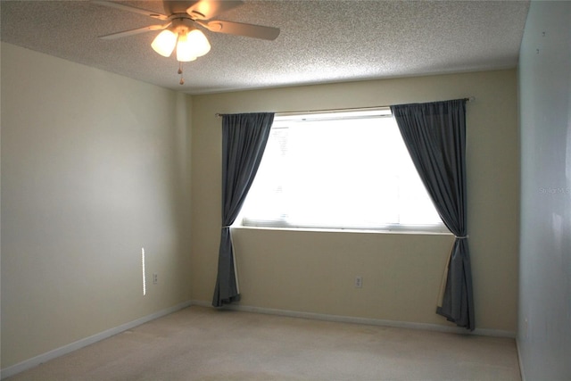 unfurnished room featuring ceiling fan, light colored carpet, and a textured ceiling