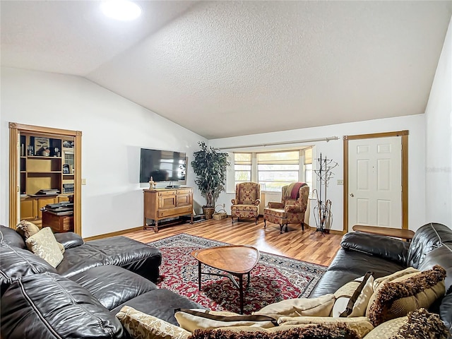 living area featuring lofted ceiling, a textured ceiling, and wood finished floors