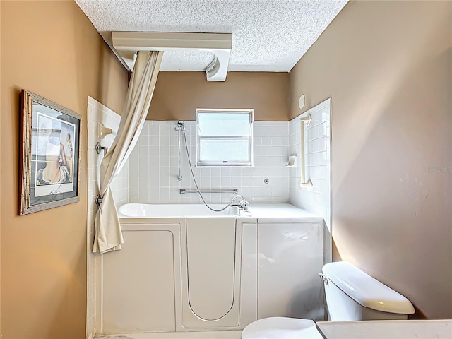 bathroom featuring a textured ceiling, toilet, and bathing tub / shower combination