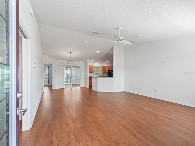 unfurnished living room with vaulted ceiling, ceiling fan, hardwood / wood-style floors, and a textured ceiling