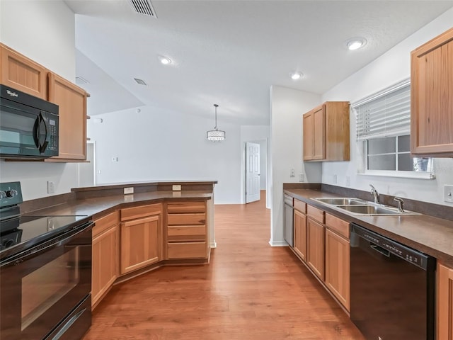 kitchen with decorative light fixtures, black appliances, sink, light hardwood / wood-style floors, and kitchen peninsula