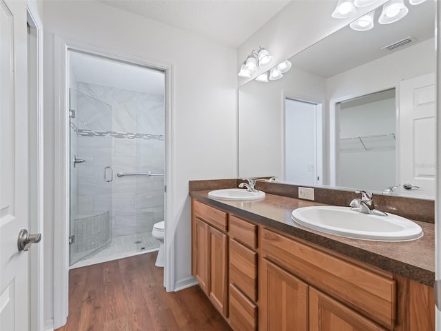 bathroom with hardwood / wood-style flooring, vanity, toilet, and a shower with shower door