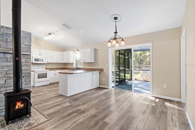 kitchen featuring a wood stove, sink, white cabinets, kitchen peninsula, and white appliances