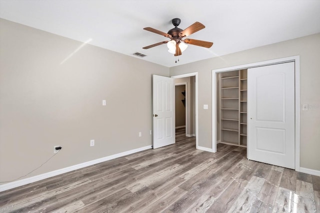 unfurnished bedroom featuring hardwood / wood-style flooring, ceiling fan, and a closet