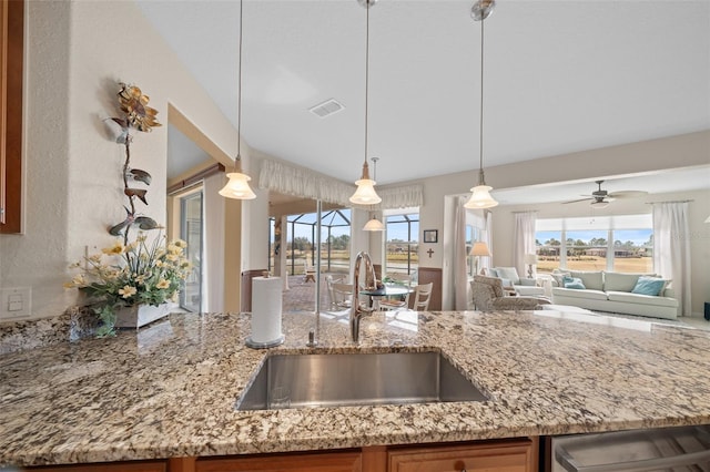 kitchen with sink, light stone counters, dishwasher, pendant lighting, and ceiling fan