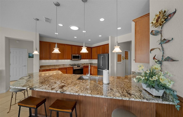 kitchen featuring pendant lighting, appliances with stainless steel finishes, kitchen peninsula, and light stone countertops