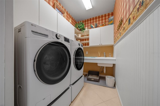 laundry room featuring cabinets, washer and clothes dryer, and light tile patterned floors