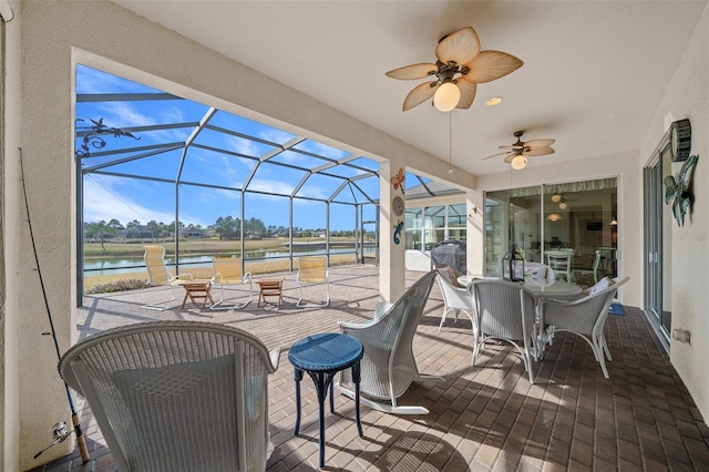 view of patio with ceiling fan, glass enclosure, and a water view