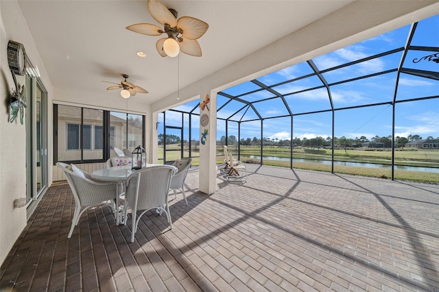 deck featuring a lanai, a patio, ceiling fan, and a water view