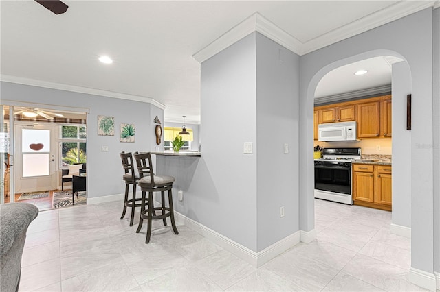 kitchen with crown molding, a breakfast bar, ceiling fan, and white appliances