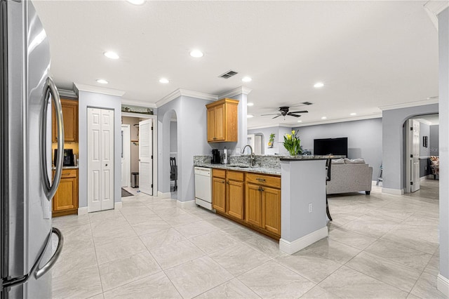 kitchen with sink, stainless steel fridge, ceiling fan, white dishwasher, and light stone counters