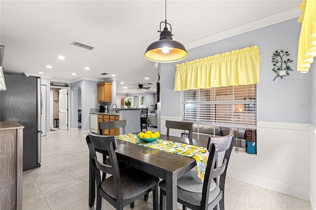 dining space with sink, crown molding, and ceiling fan