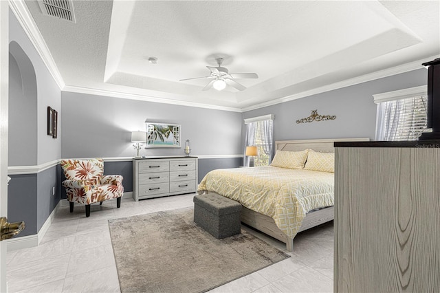 tiled bedroom featuring multiple windows, ornamental molding, a textured ceiling, and a tray ceiling