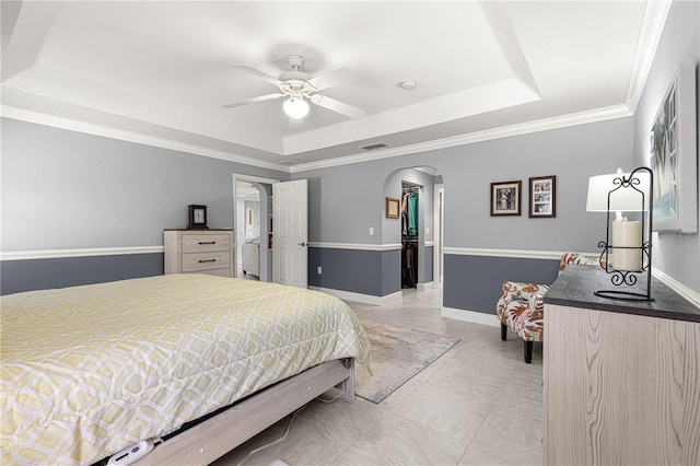 bedroom featuring a walk in closet, ornamental molding, a raised ceiling, and a closet