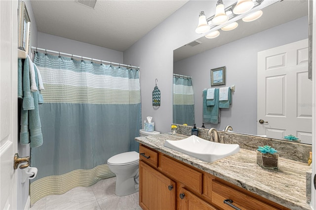 bathroom featuring vanity, tile patterned floors, a textured ceiling, and toilet