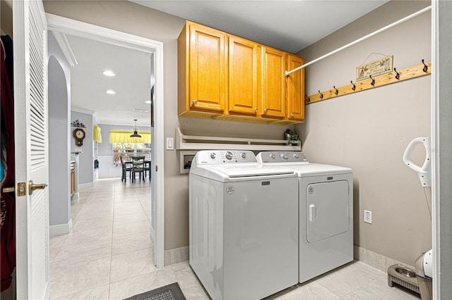 clothes washing area featuring cabinets, washing machine and dryer, and light tile patterned floors