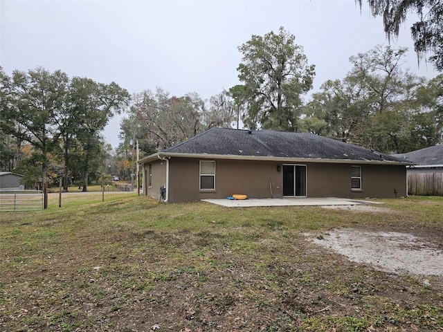 back of house with a lawn and a patio