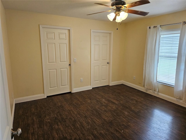 unfurnished bedroom featuring multiple windows, dark wood-type flooring, and ceiling fan