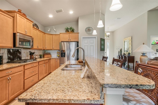 kitchen featuring appliances with stainless steel finishes, a kitchen island with sink, a breakfast bar area, and sink