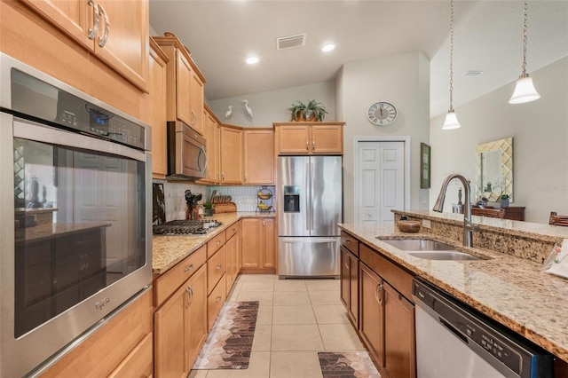 kitchen featuring vaulted ceiling, decorative light fixtures, tasteful backsplash, sink, and stainless steel appliances