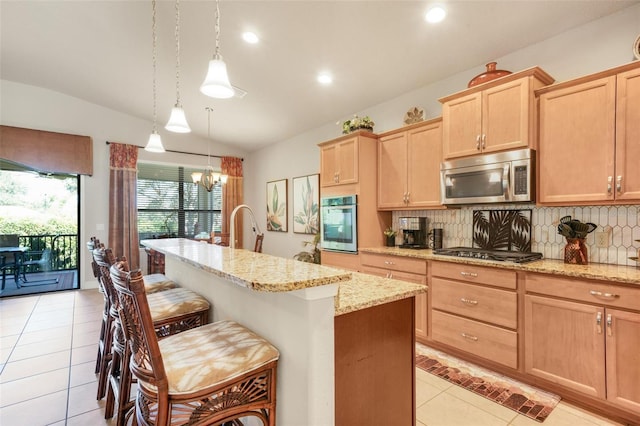 kitchen featuring backsplash, stainless steel appliances, an island with sink, a kitchen bar, and vaulted ceiling