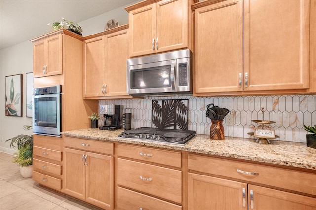 kitchen with light tile patterned floors, stainless steel appliances, tasteful backsplash, light stone counters, and light brown cabinets