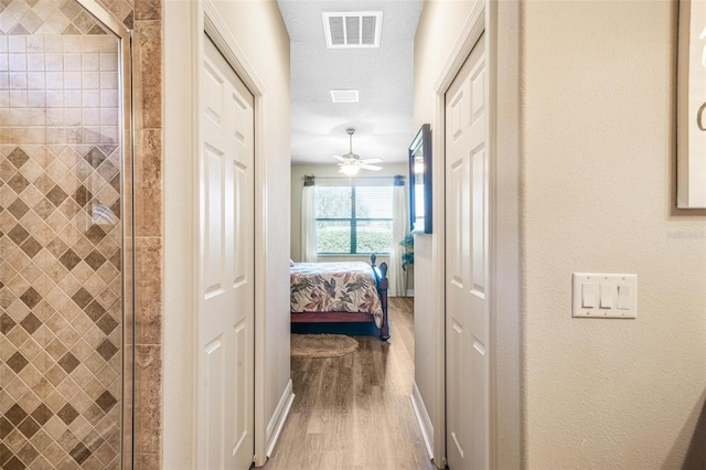 hall with hardwood / wood-style flooring and a textured ceiling