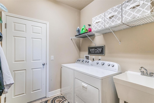 washroom with tile patterned floors, separate washer and dryer, sink, and a textured ceiling