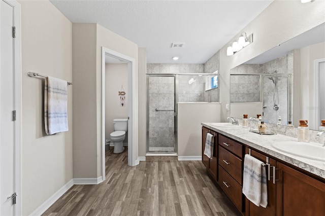 bathroom featuring vanity, hardwood / wood-style flooring, toilet, and walk in shower