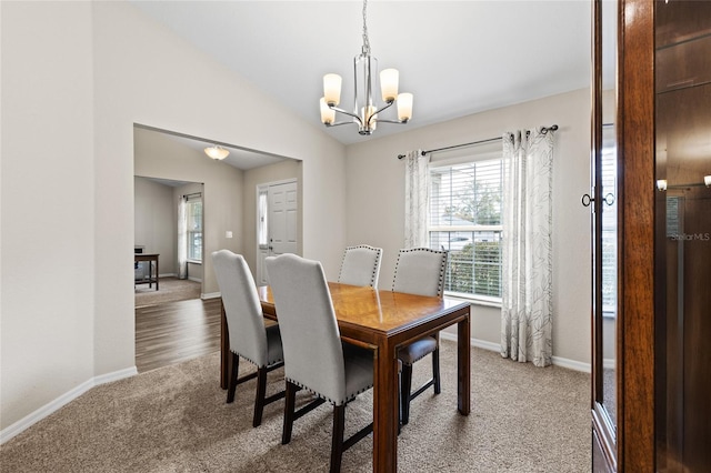 carpeted dining room with lofted ceiling and an inviting chandelier